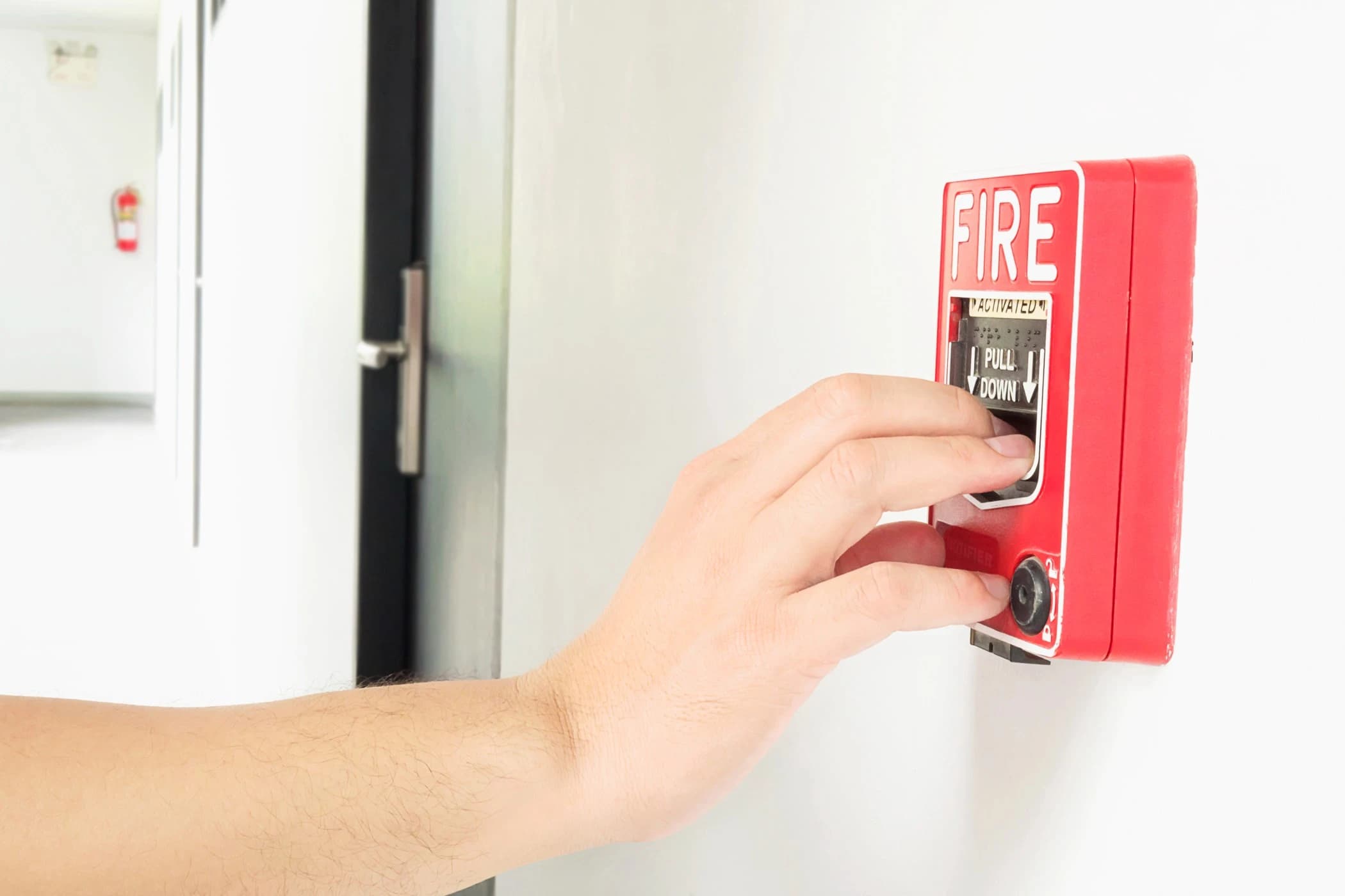 electrician is reaching his hand push fire alarm